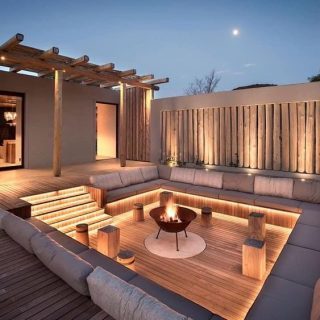 Espace extérieur moderne avec salon, feu de camp et éclairage doux.