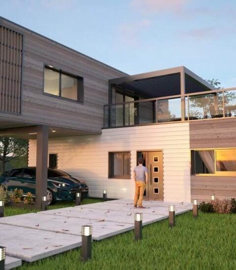 Maison moderne avec terrasse, jardin et allée éclairée, un homme à la porte.