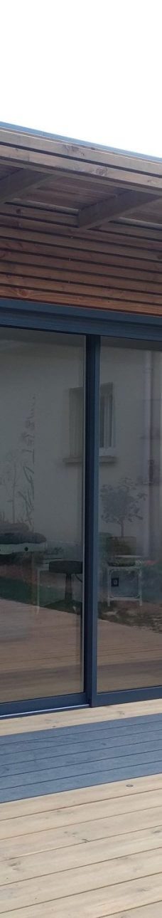 Façade moderne avec de grandes fenêtres et un toit en bois.